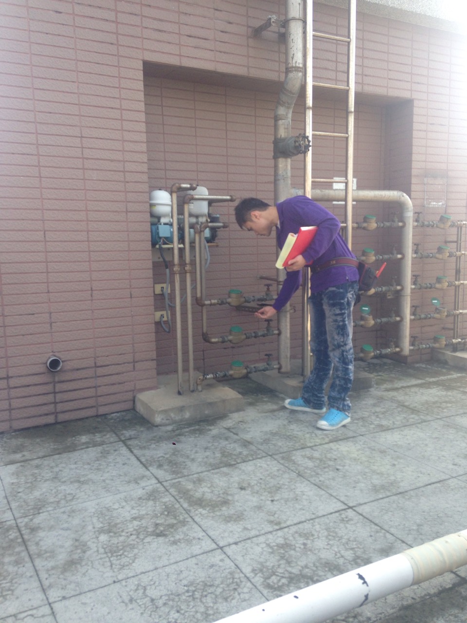 工程師巡檢大樓屋頂水錶與管線設備，記錄設施運作情形