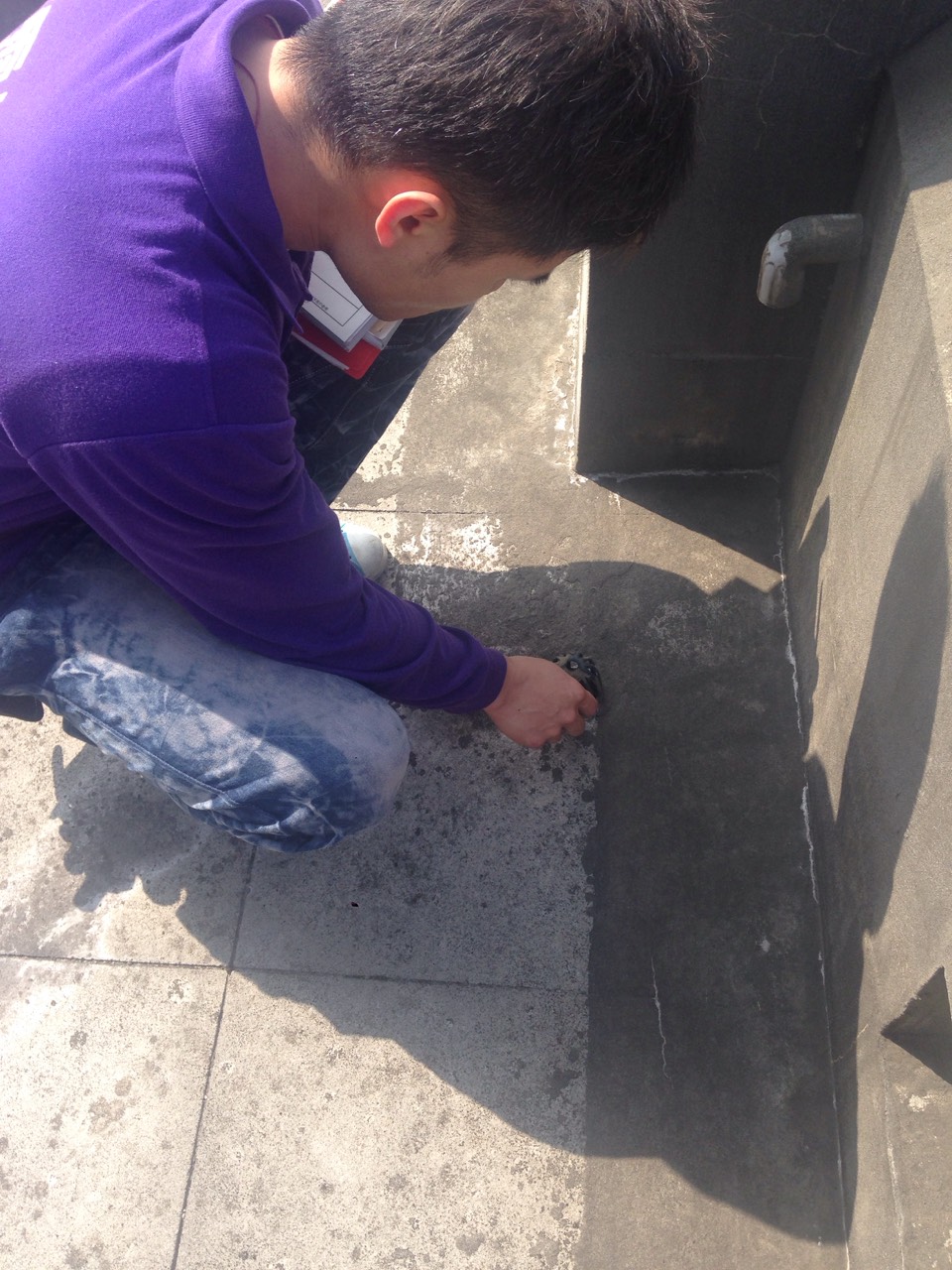 工程師在屋頂檢查排水孔及防水狀況，進行建築維護