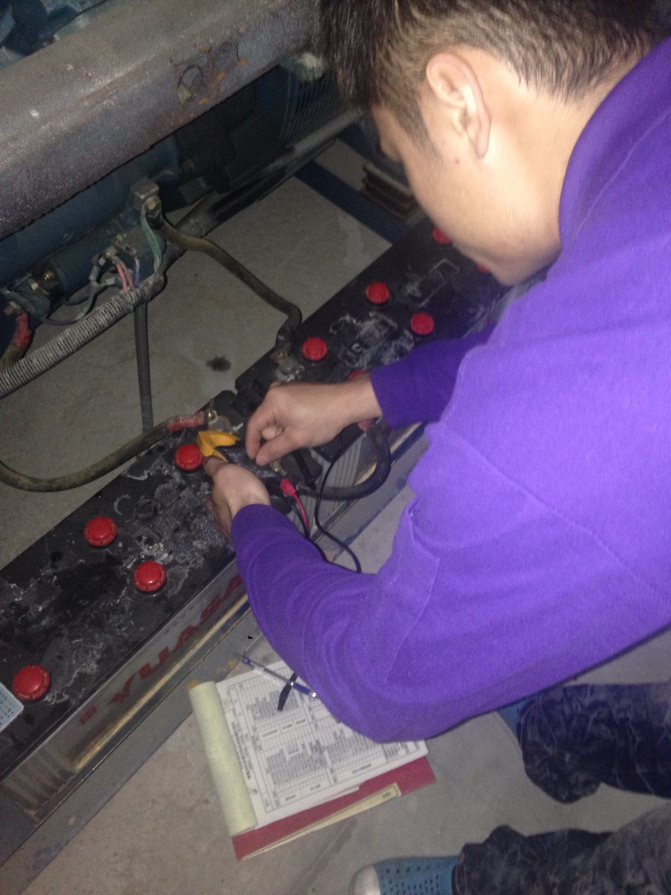 工程師使用電錶測試柴油發電機組電池電壓，記錄檢查數據