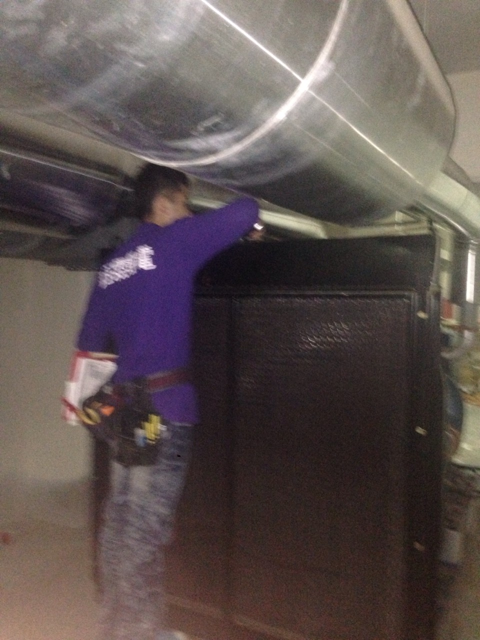 工程師於機房天花板下檢查大型通風管線，執行空調與排風設備維護