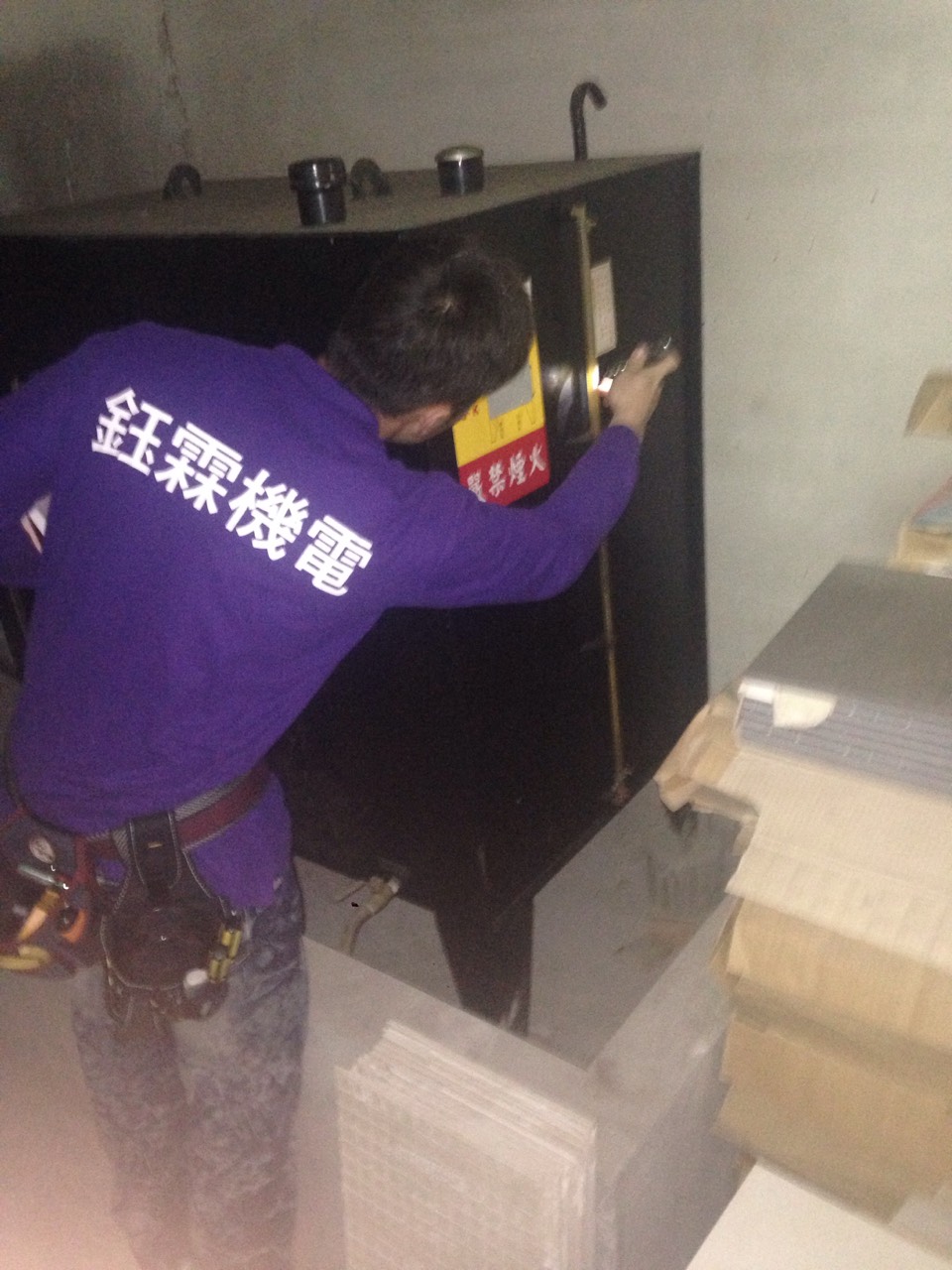 工程師使用手電筒檢查大型油箱，確保消防設施安全