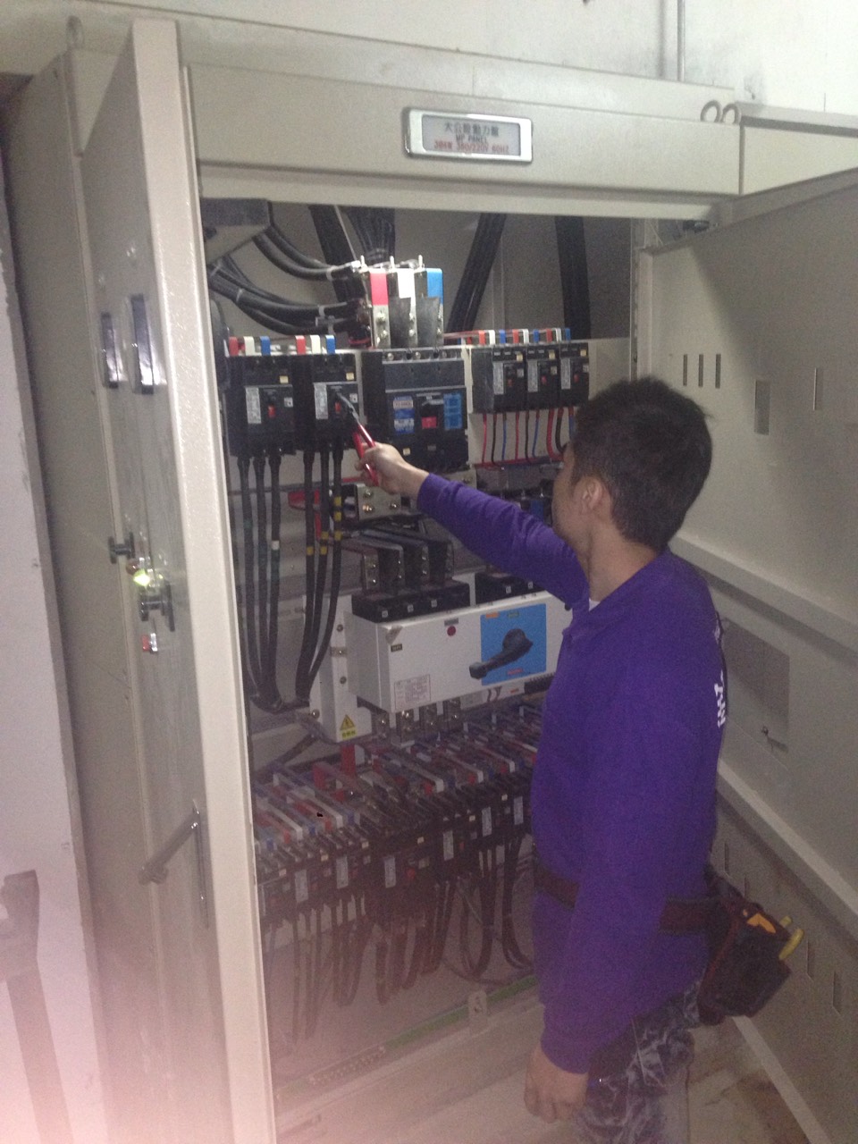 工程師使用測電筆測試主電源配電盤，確保電力設備安全