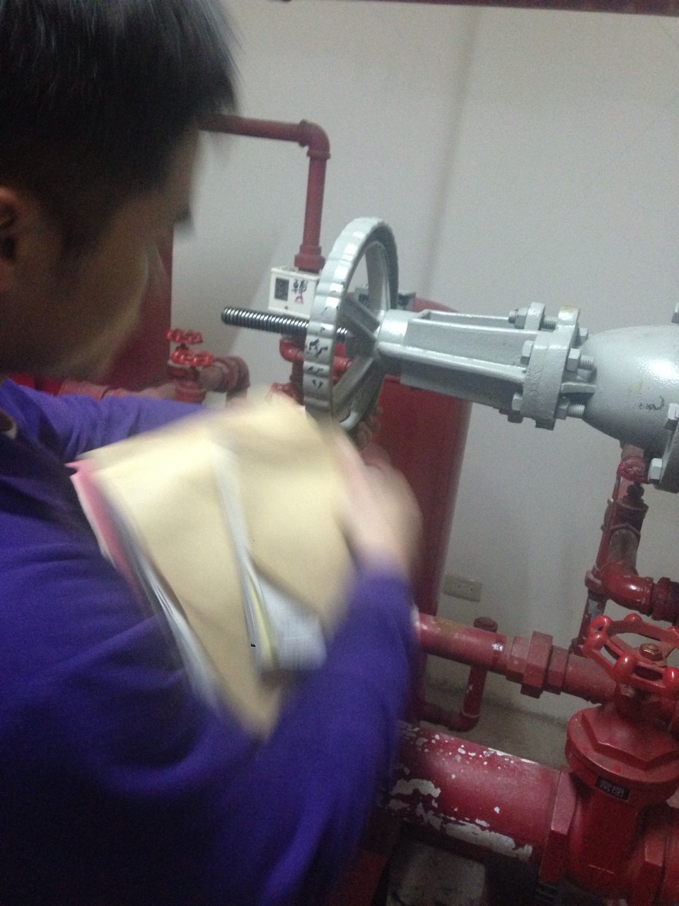 現場人員操作大型閥門，記錄消防管線水壓測試數據