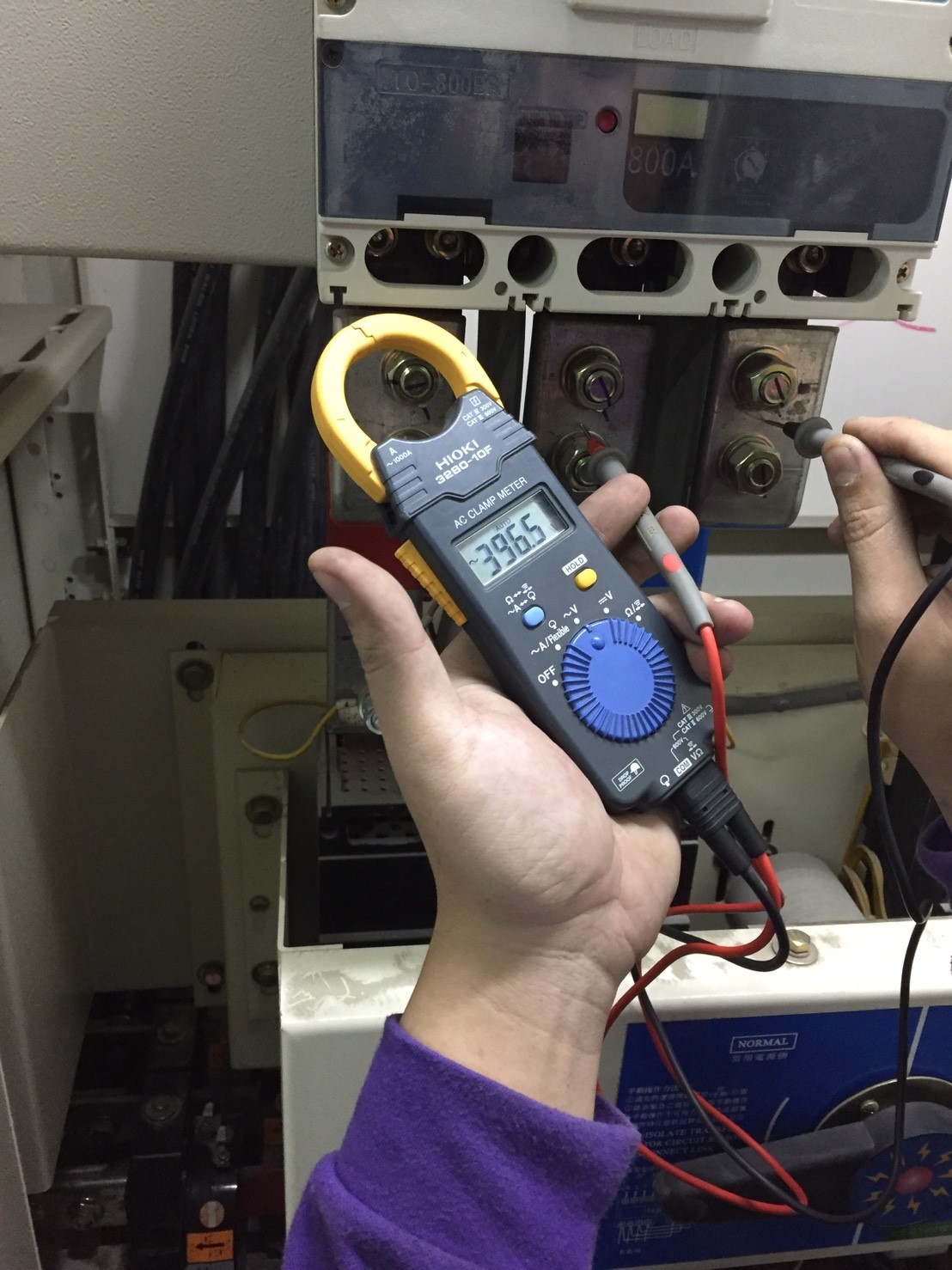 工程師使用鉗形電流表量測配電盤電壓，進行設備安全檢查