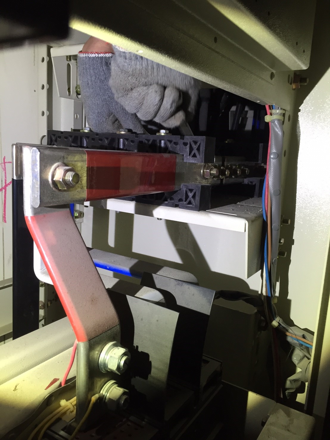 工程師佩戴手套於配電盤內調整母線螺栓，執行設備巡檢保養