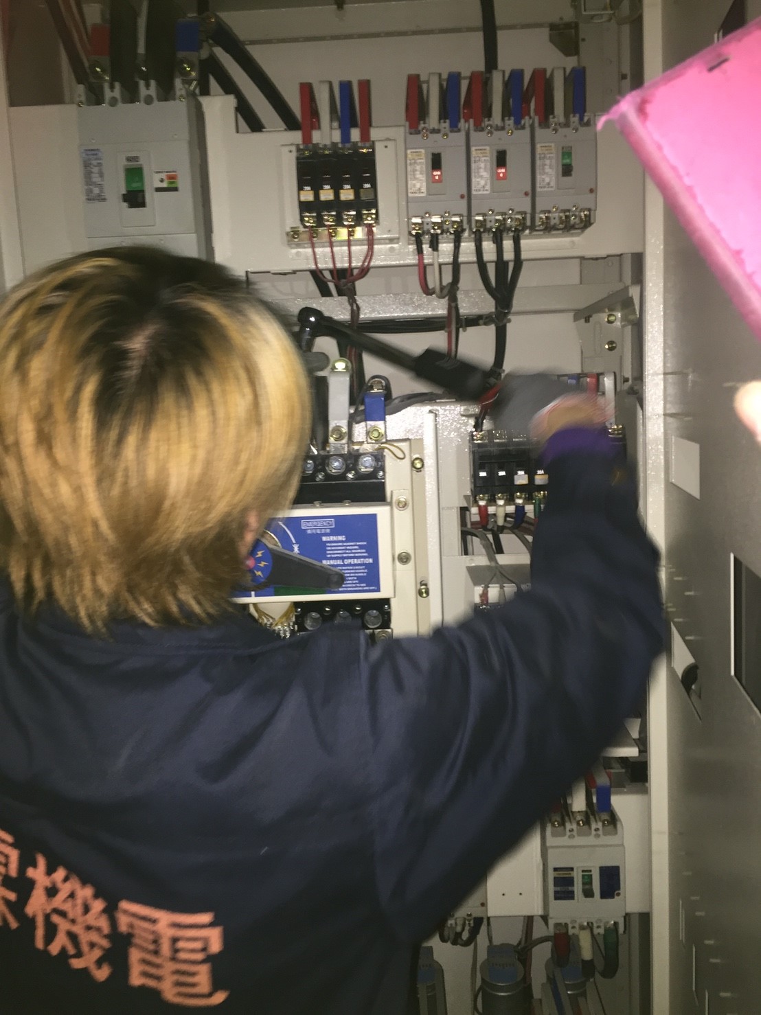 工程師於配電盤內檢查電路狀態，維護大樓電氣系統